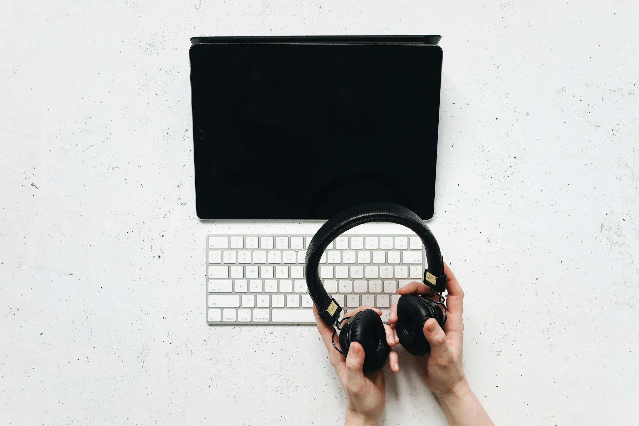 Top view of a digital workspace with tablet, keyboard, and headphones.